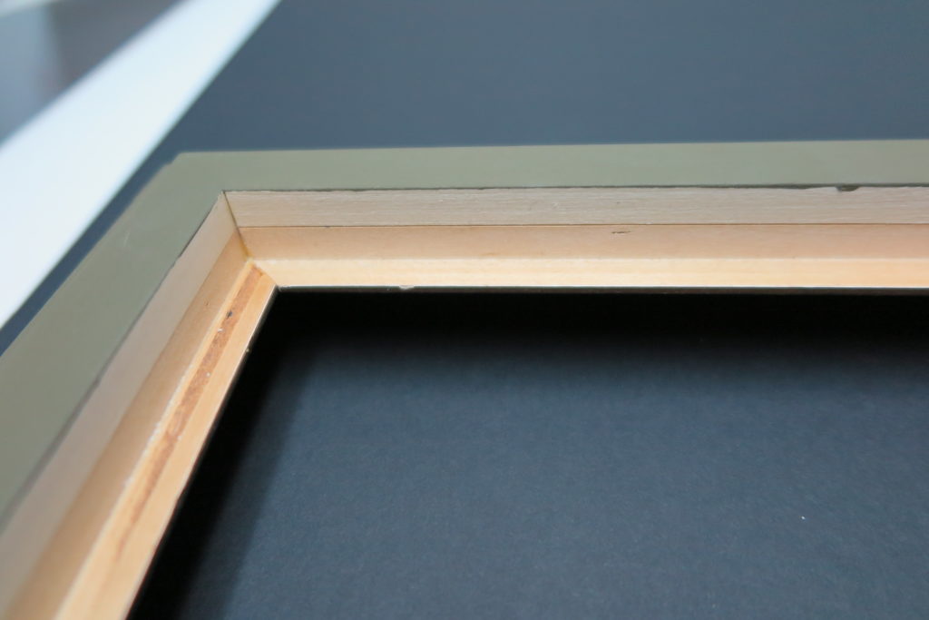 Close-up of a wooden frame corner showing layered construction for artwork mounting.