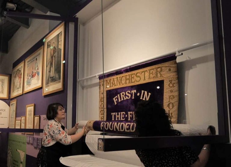 Rehanging the Manchester suffragette banner "Manchester First in the Fight"