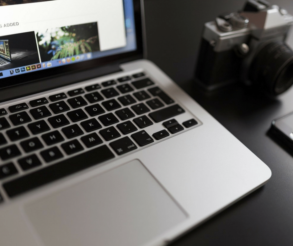 Photography business workspace with camera, laptop, and marketing materials for professional photographers.
