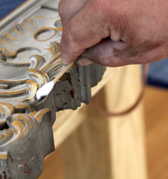 Detailed view of a conservator carefully using swabs to clean artifacts, removing fine soot residue from surfaces.