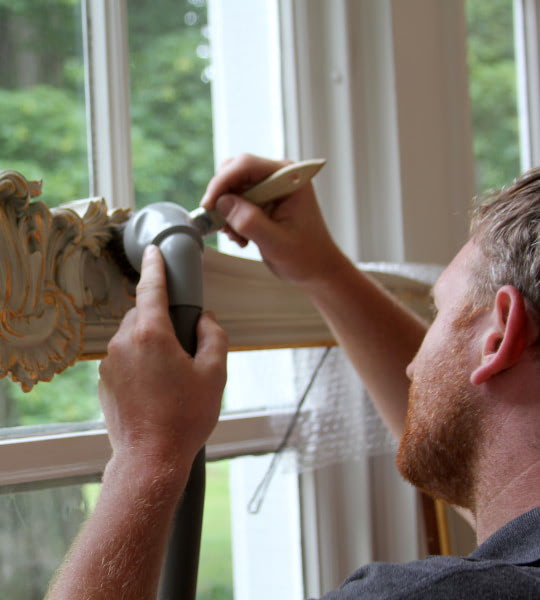 Conservators using HEPA-filtered vacuum cleaners to remove dry soot from library or museum collection.